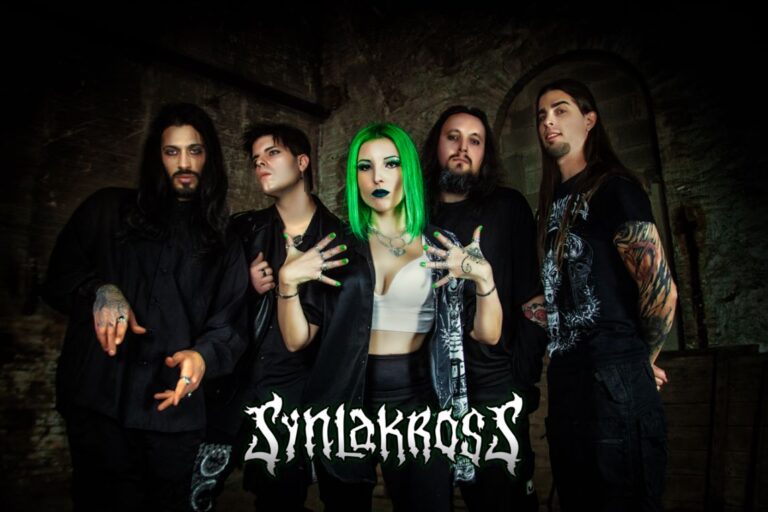 A photo of the current line-up of Synlakross band members standing beside each other in a darkened room